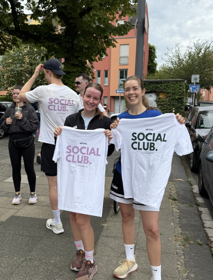 Zwei Personen halten strive. T-Shirts in Flieder und Grün hoch